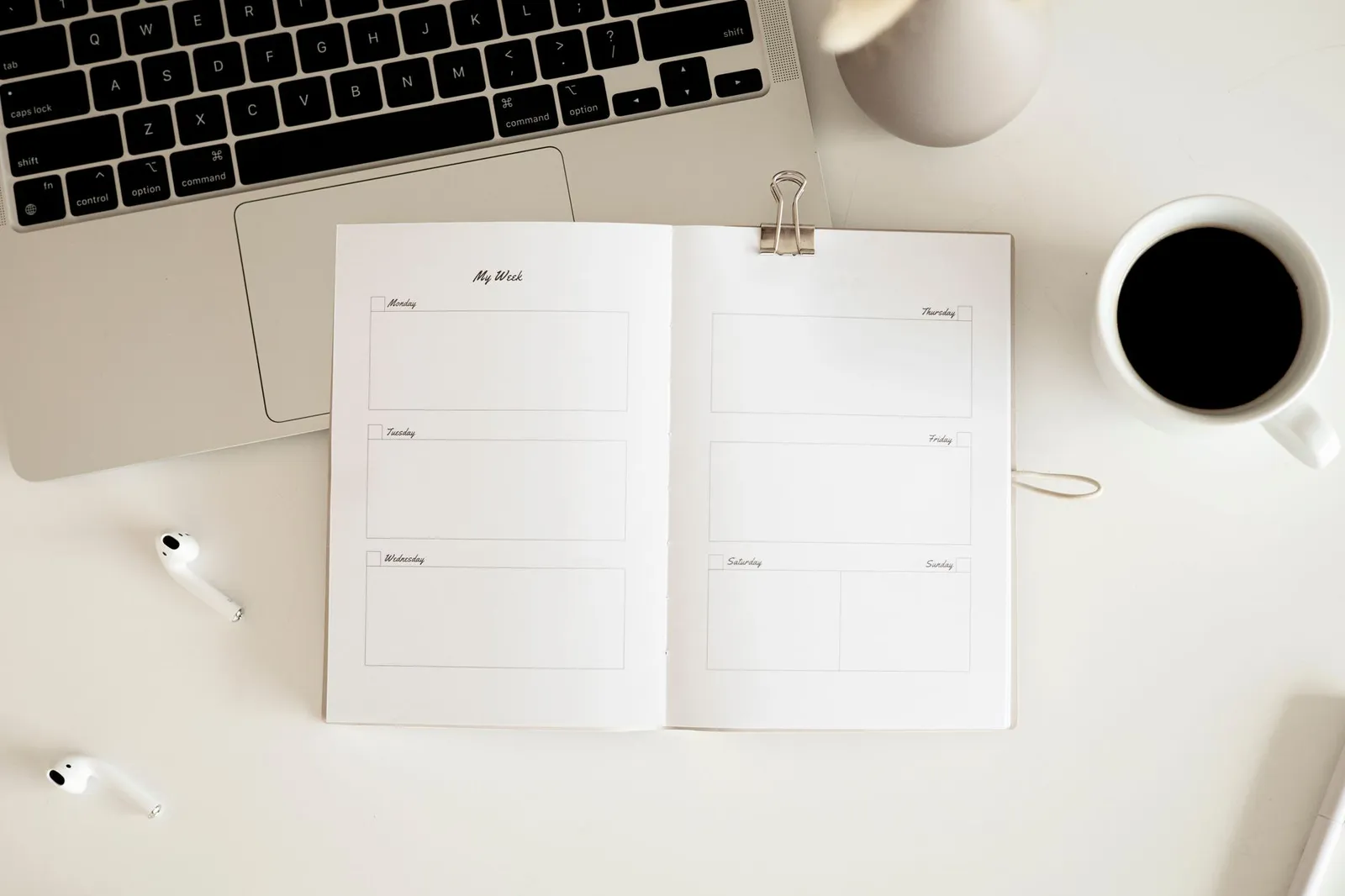A laptop showing a weekly schedule beside a coffee cup and notebook
