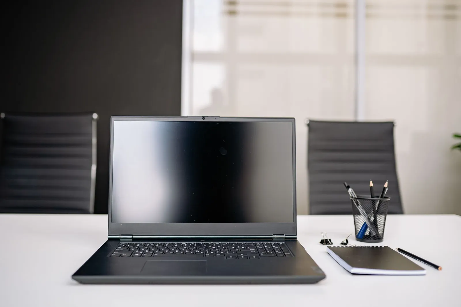 An empty desk with a closed laptop and a notebook